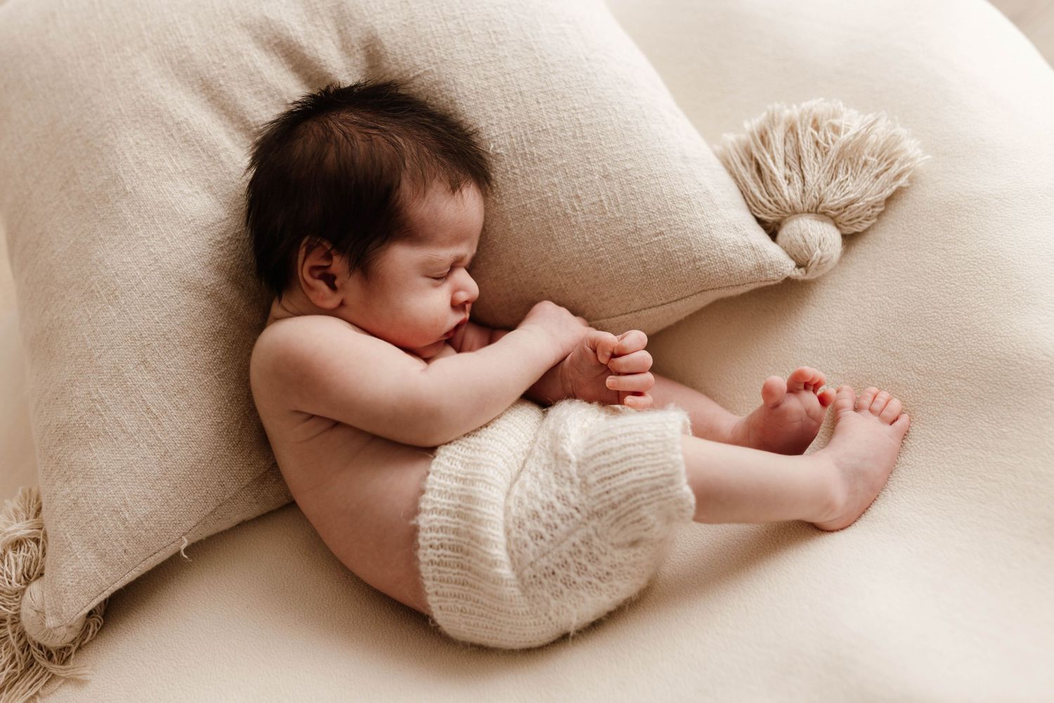 Gentle newborn baby photography with soft neutral tones and cozy textures.