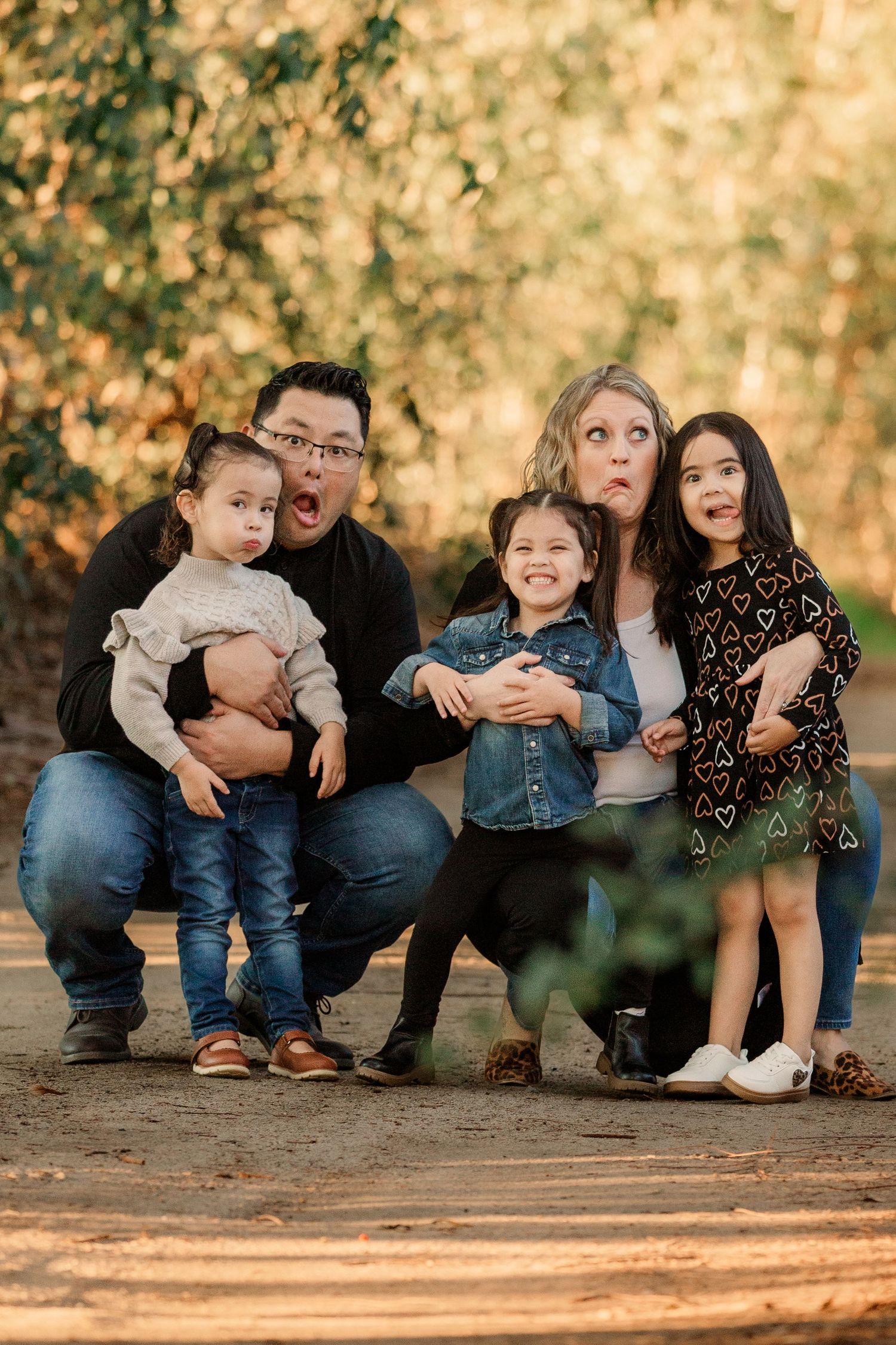 A family group poses together on the ground in warm autumn lighting.