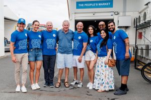 Group of volunteers in blue shirts gathered outside The People's Market building.