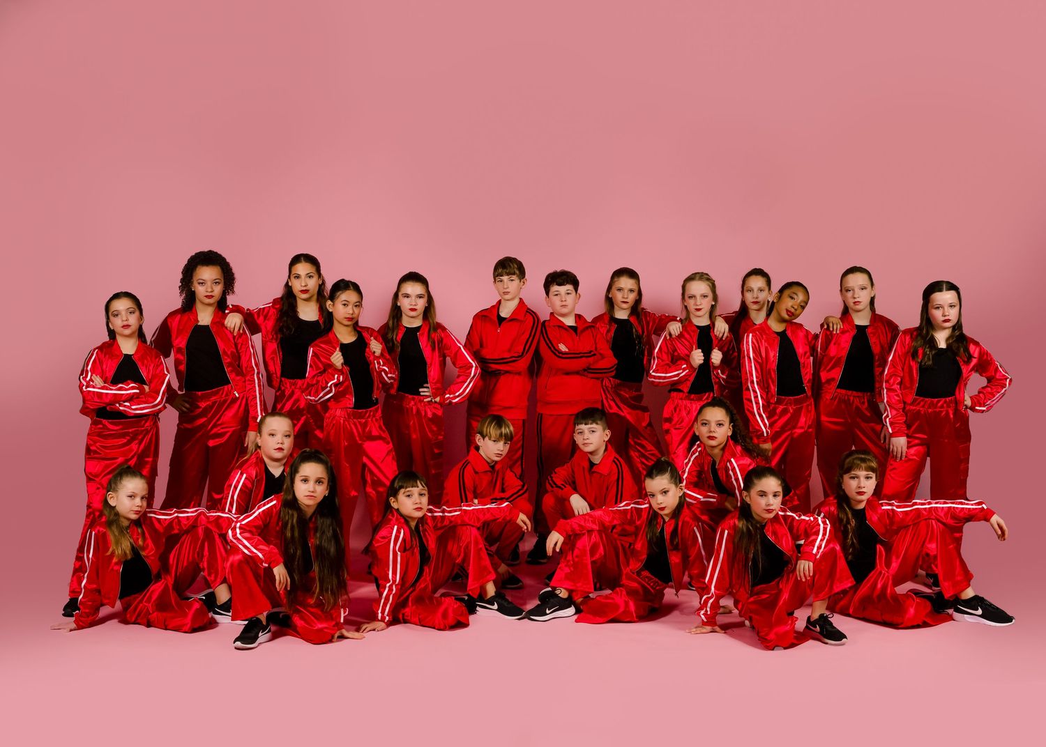 Energetic dance ensemble performs in pink and black costumes on stage.