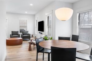Modern open concept living and dining area with round wood table, gray chairs, and distinctive dome pendant light.