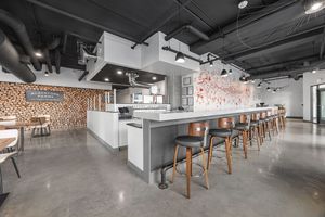 Modern industrial bar interior with long counter, bar stools, polished concrete floors, and artistic wood accent wall.