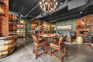 Rustic bar lounge with brick walls, barrel decor, wood furniture, and warm chandelier lighting.