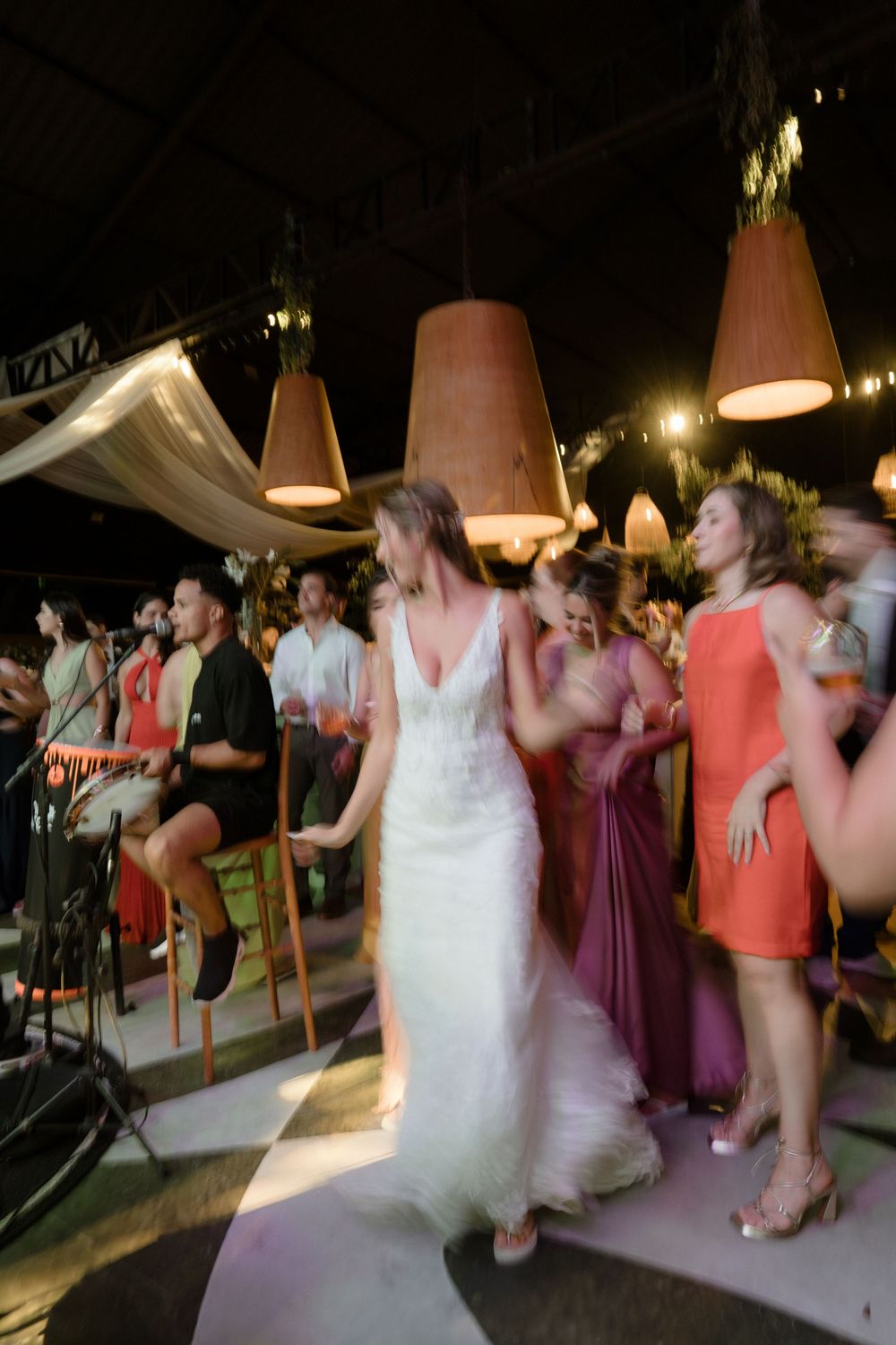Wedding party guests dance energetically on a lively dance floor during an evening reception celebration.