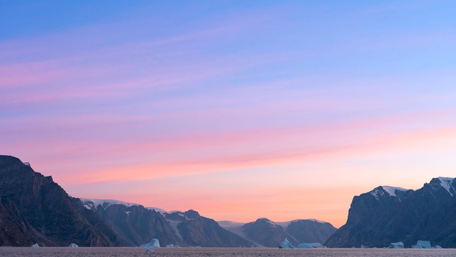 Majestic mountain range silhouetted against a pink and purple sunset sky.