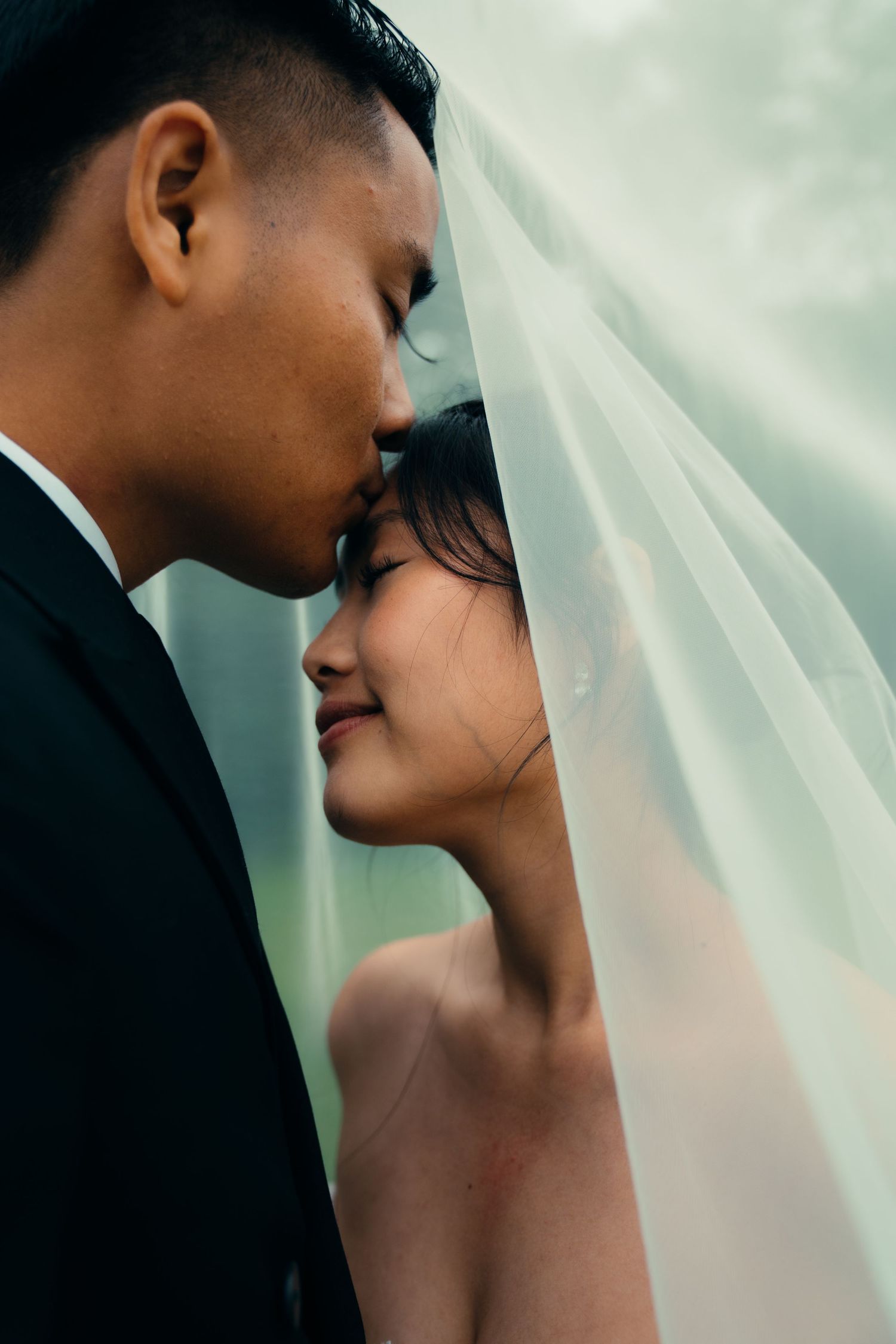 Intimate close-up of bride and groom sharing a tender moment under a flowing bridal veil.