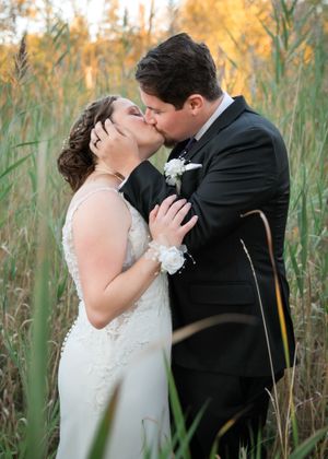 A romantic wedding kiss captured among tall autumn grasses.
