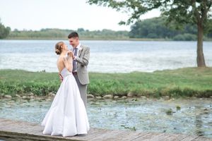 Wedding couple shares an intimate moment on a dock by a serene lake.