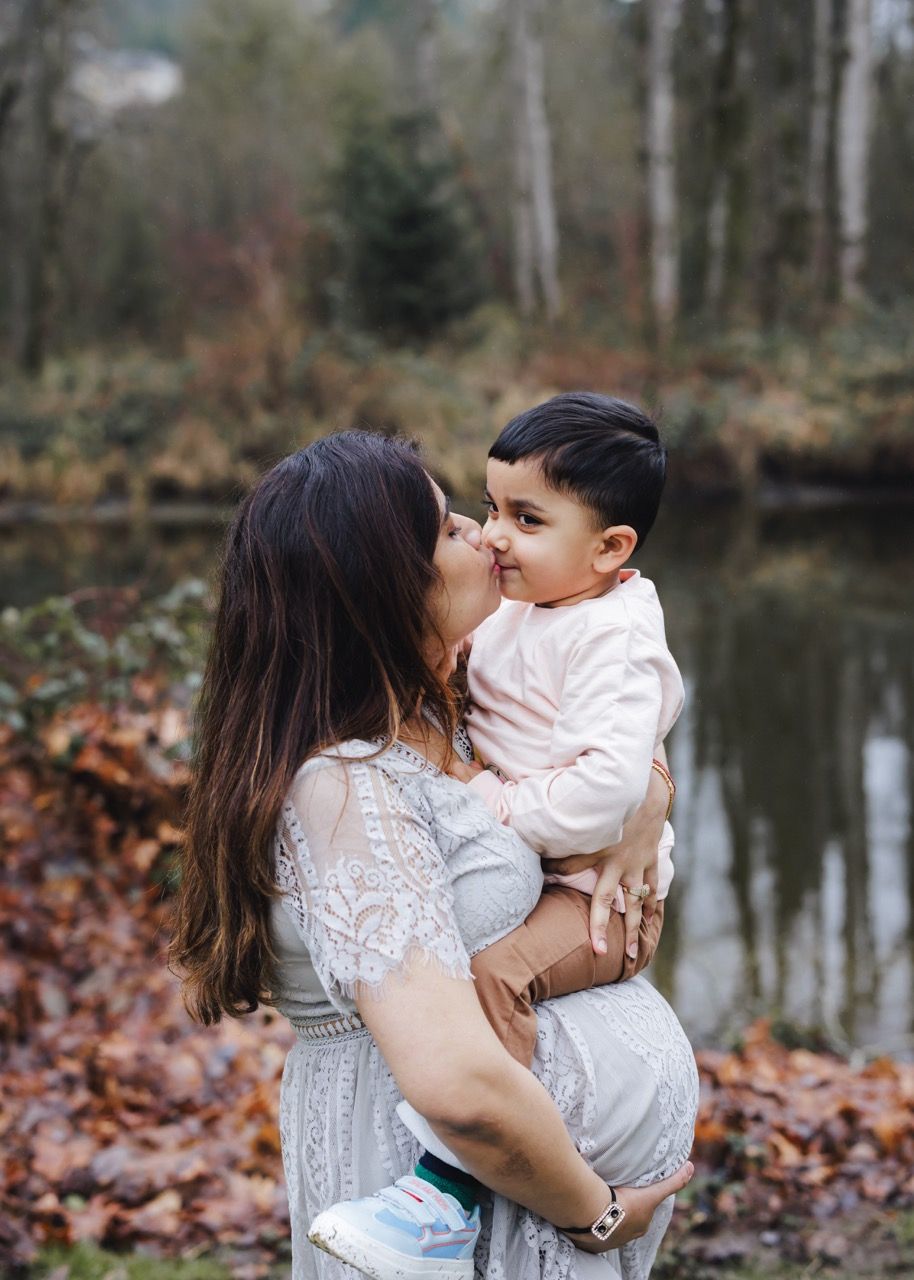Toddler hugging mother's baby bump in a Snohomish park. Affectionate family maternity session by Tim Neal.
