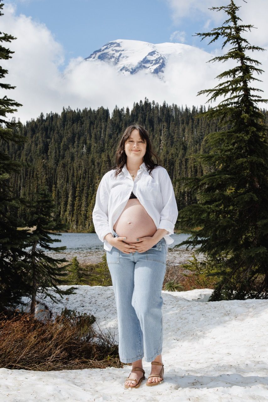 Expecting mom standing in front of mountain mount rainier national park. Tim Neal captures the adventure of the motherhood journey.