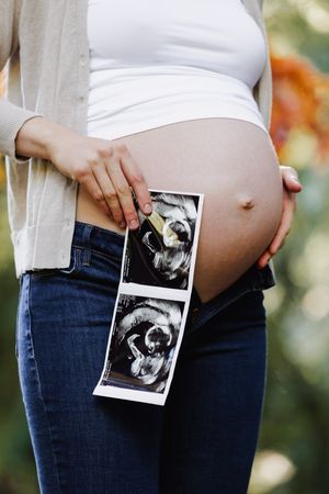 Close-up of parents' hands on baby bump during a Snohomish maternity session. Warm lifestyle photography by Tim Neal.
