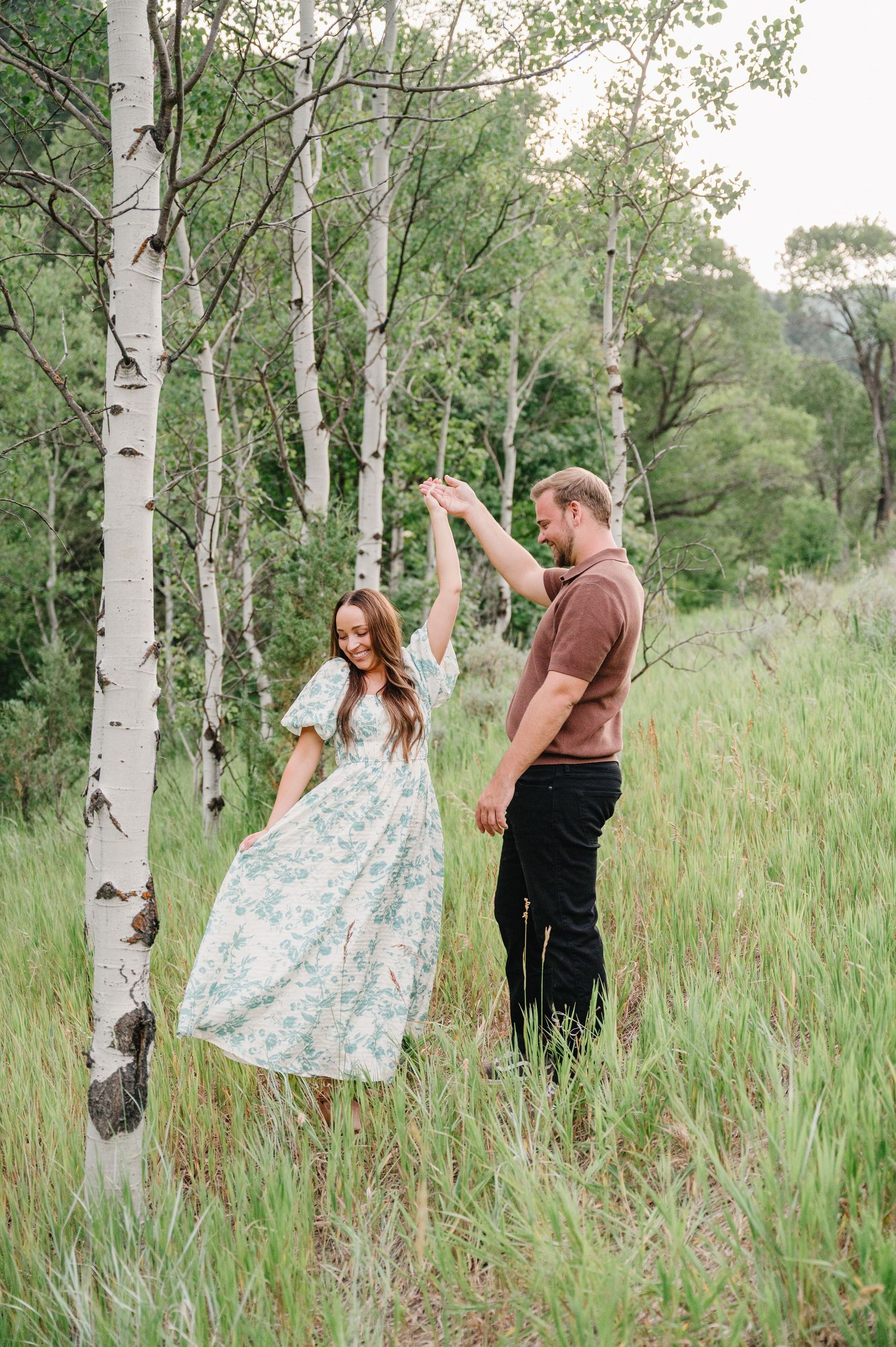 A couple dances together in a serene aspen grove with tall grass and summer greenery surrounding them.