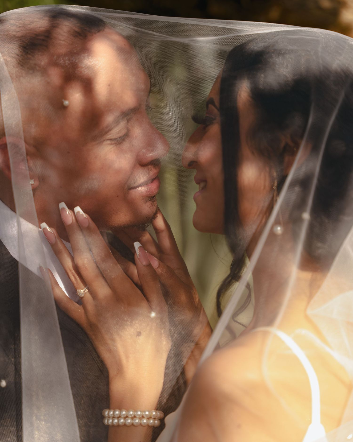 A romantic wedding portrait showing tender intimacy through a delicate veil.