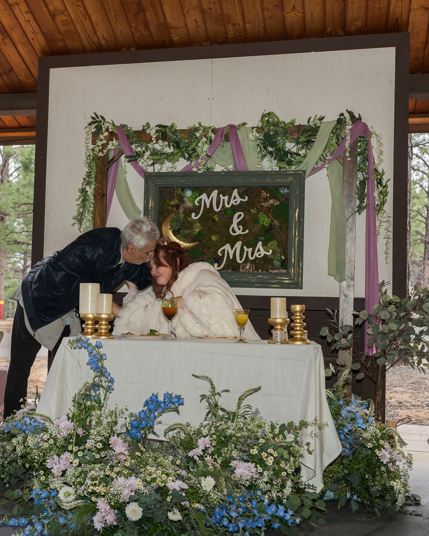 A romantic wedding scene with decorative floral garlands and a 'Mr & Mrs' sign.