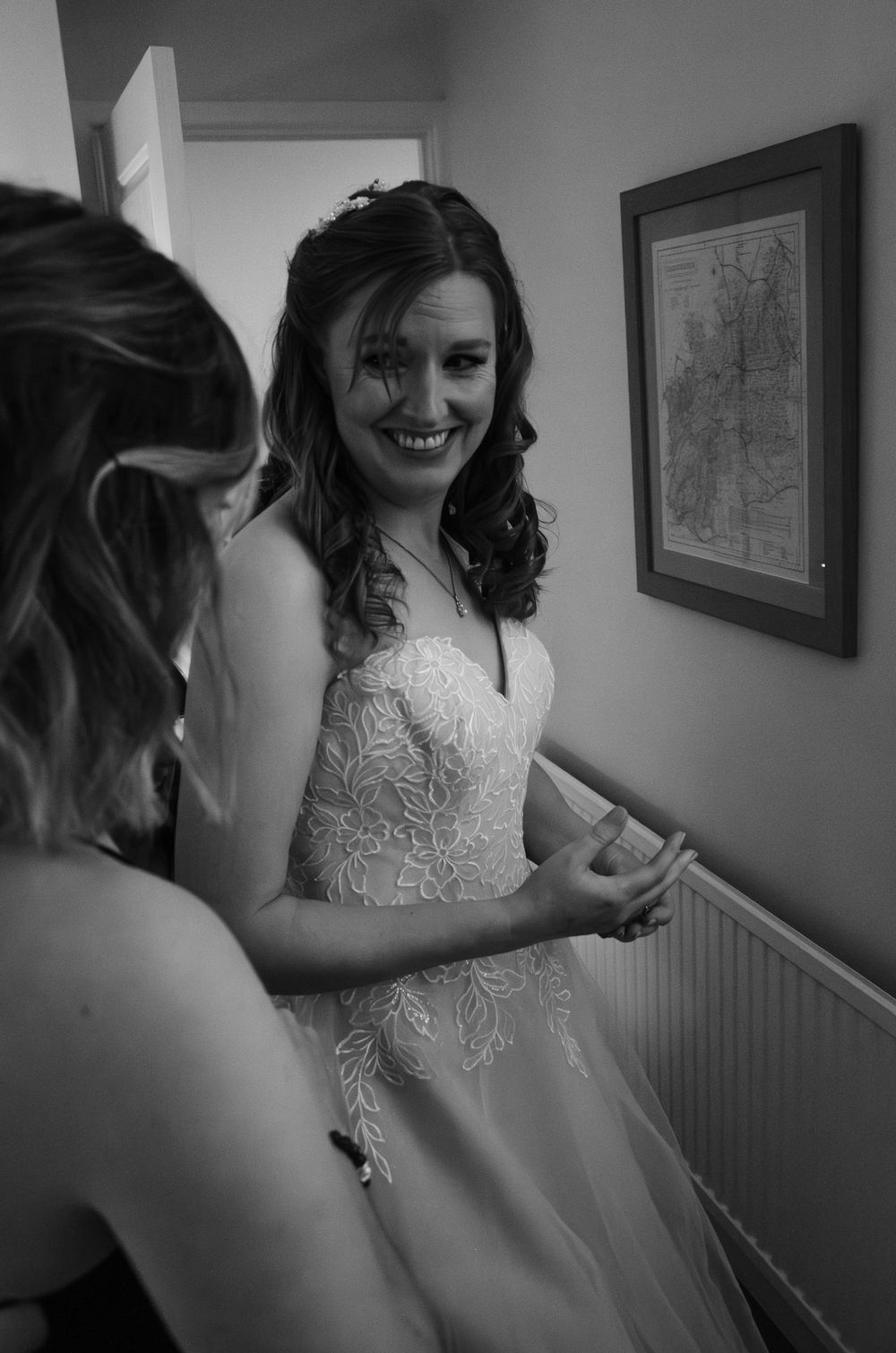 A bride in an elegant lace wedding gown smiles during her wedding preparations.