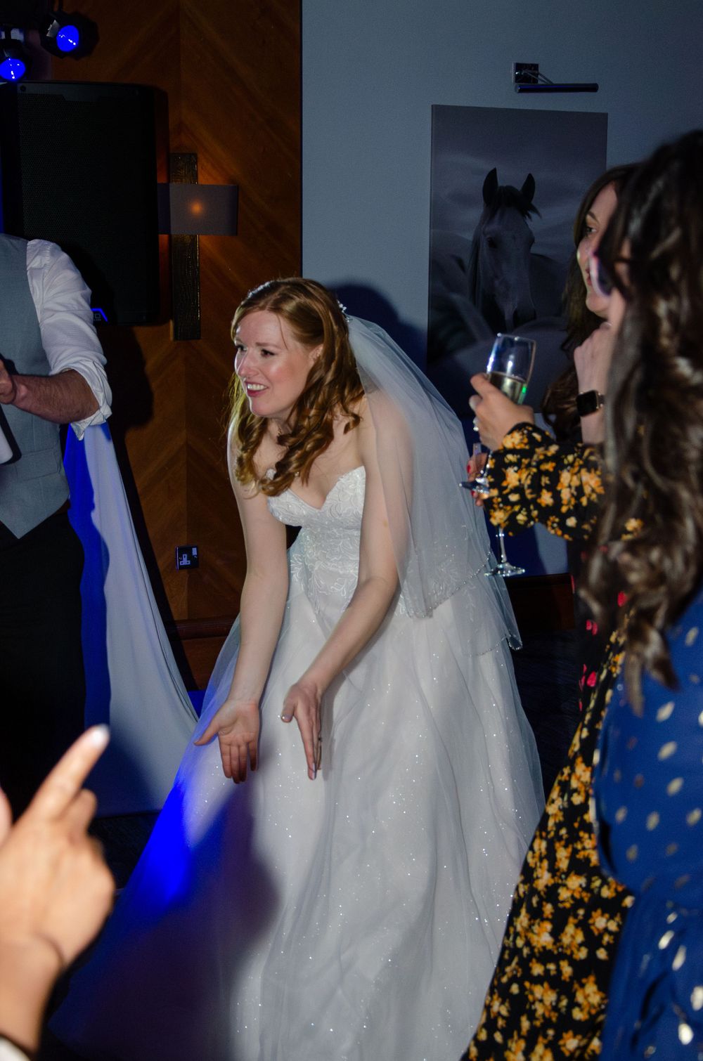 A bride in a white gown dances at her reception under blue lighting.