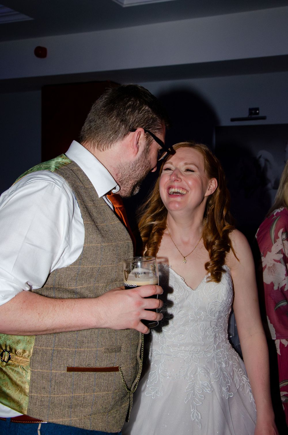 Couple sharing intimate moment on dance floor with groom in tweed vest.
