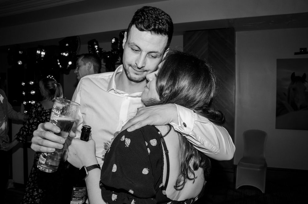 Black and white photo of people embracing at indoor party.