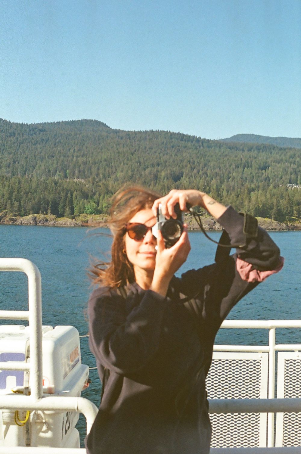 Scenic mountain backdrop over a lake with ferry railing visible in the foreground.