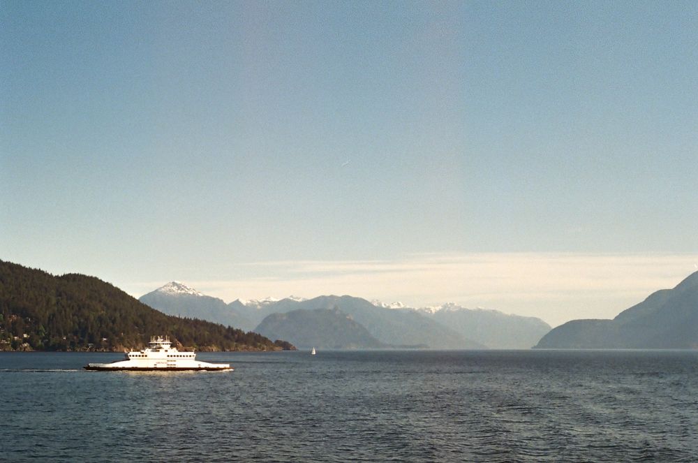 Panoramic view of mountain ranges and islands across calm waters on a clear day.