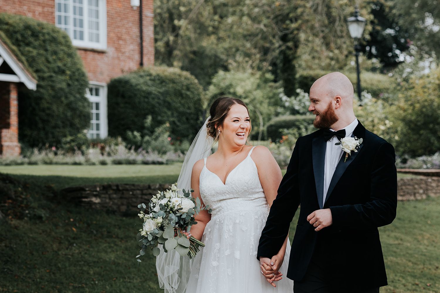 A couple shares a joyful moment on their wedding day in a garden setting.