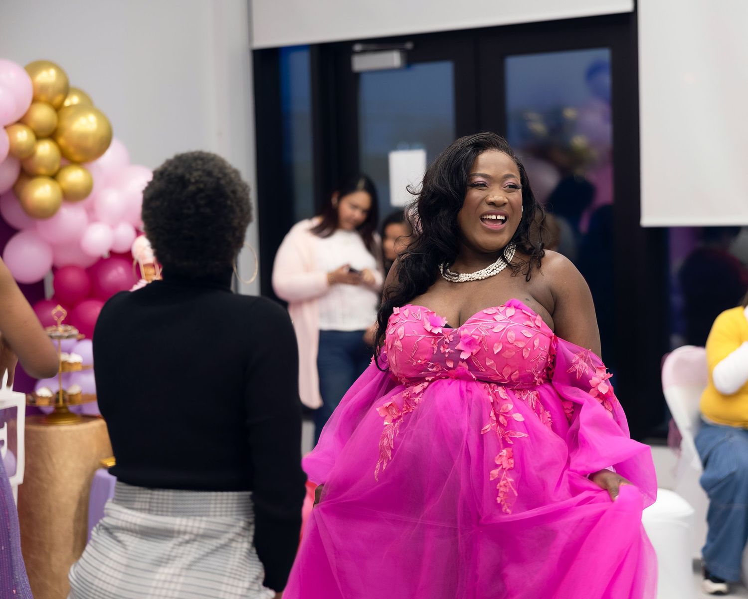 Celebration scene with person wearing vibrant pink ball gown and balloon decorations.