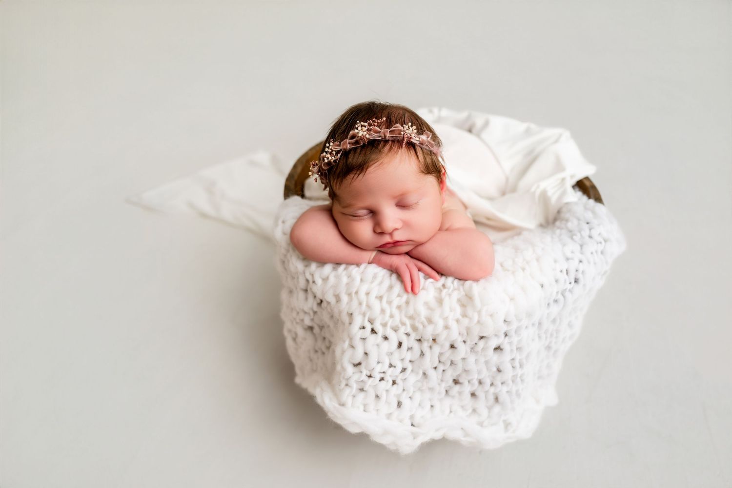 Sleeping newborn baby in delicate white lace wrap on light background.