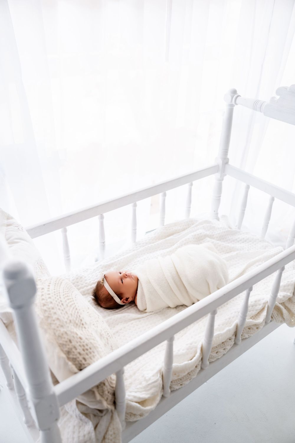 White linen bedding and pillows arranged on a cozy bed with natural sunlight streaming through.