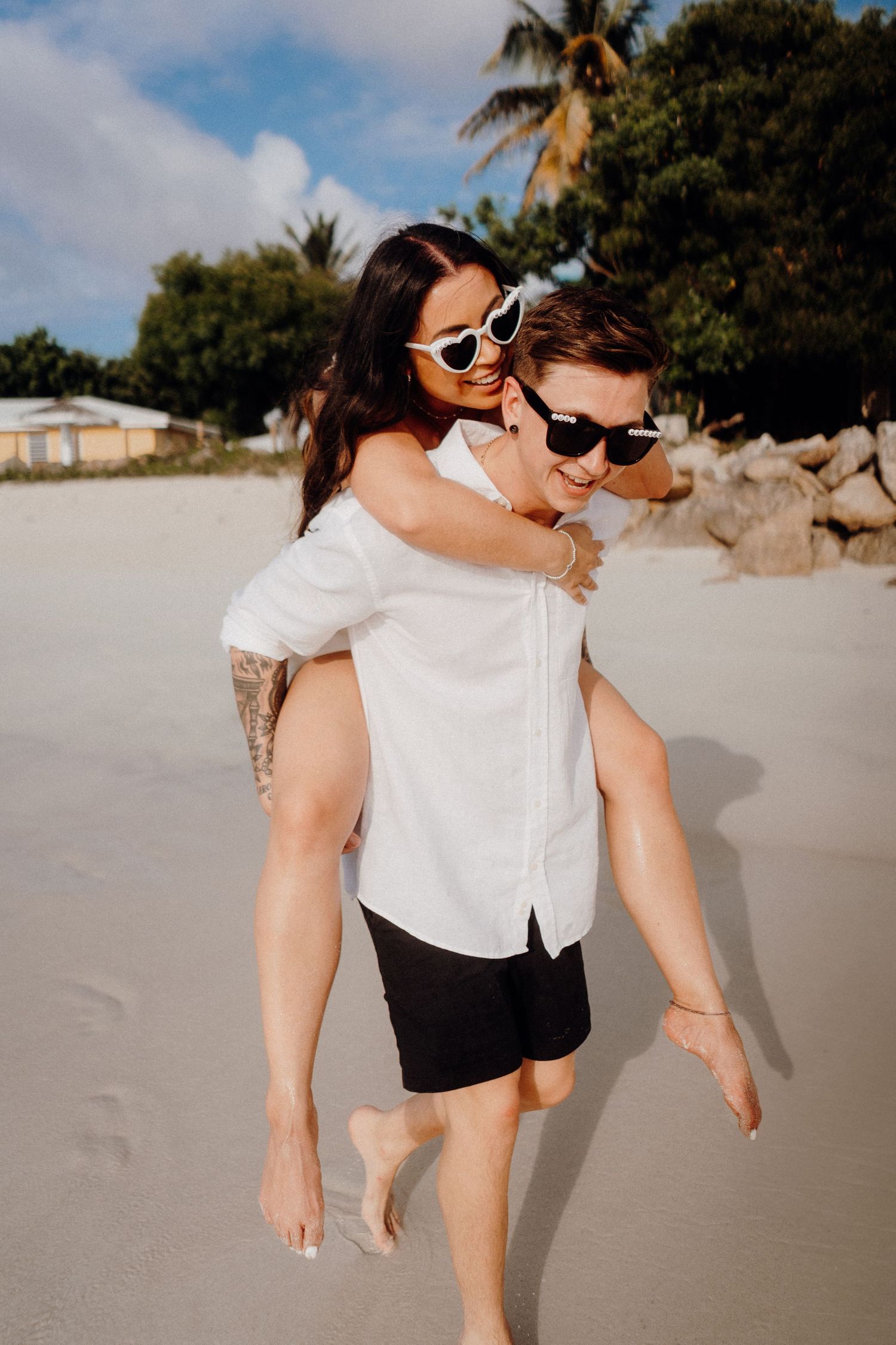 Couple having fun with piggyback ride on a sunny tropical beach.