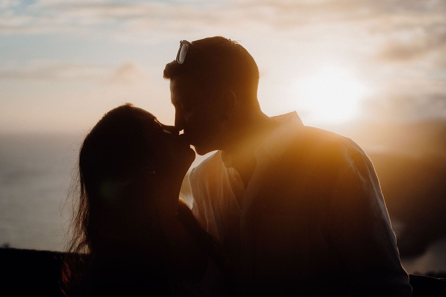 Silhouetted couple sharing intimate moment against golden sunset sky.