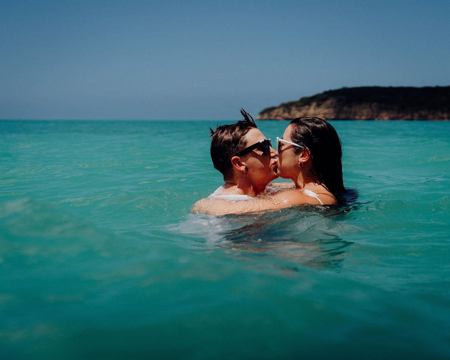 Couple sharing an intimate moment while swimming in crystal clear turquoise waters.