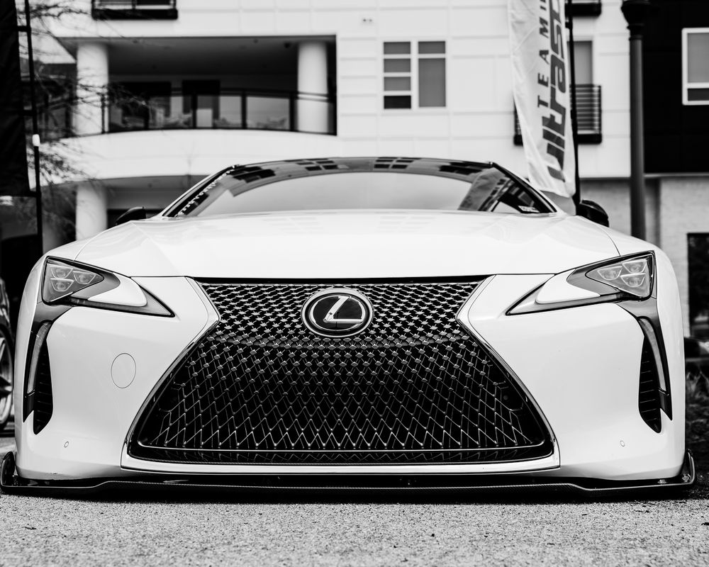 Black and white front view of white Lexus LC coupe showcasing signature spindle grille design.