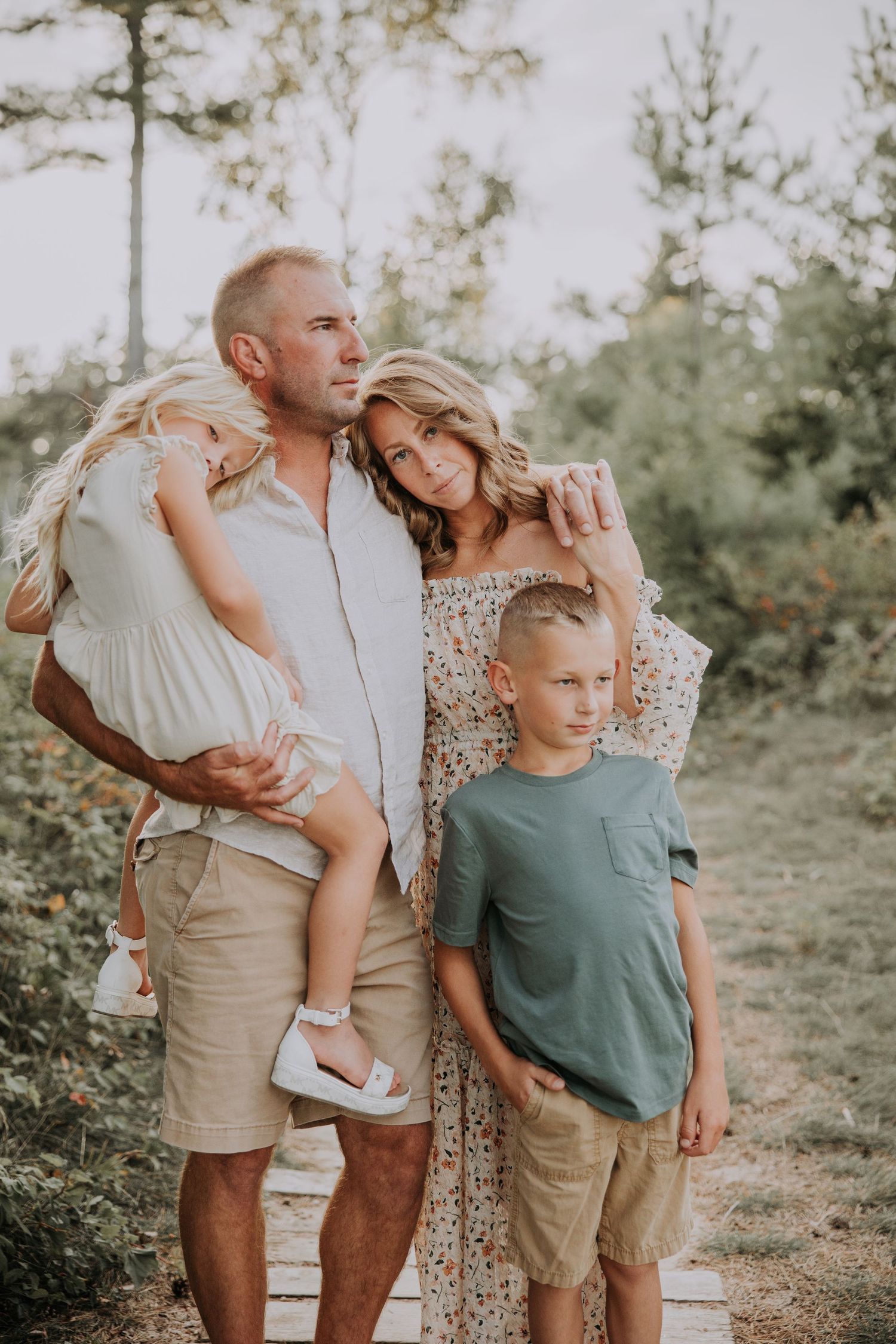 A family poses together for a portrait in a wooded field on an overcast day.