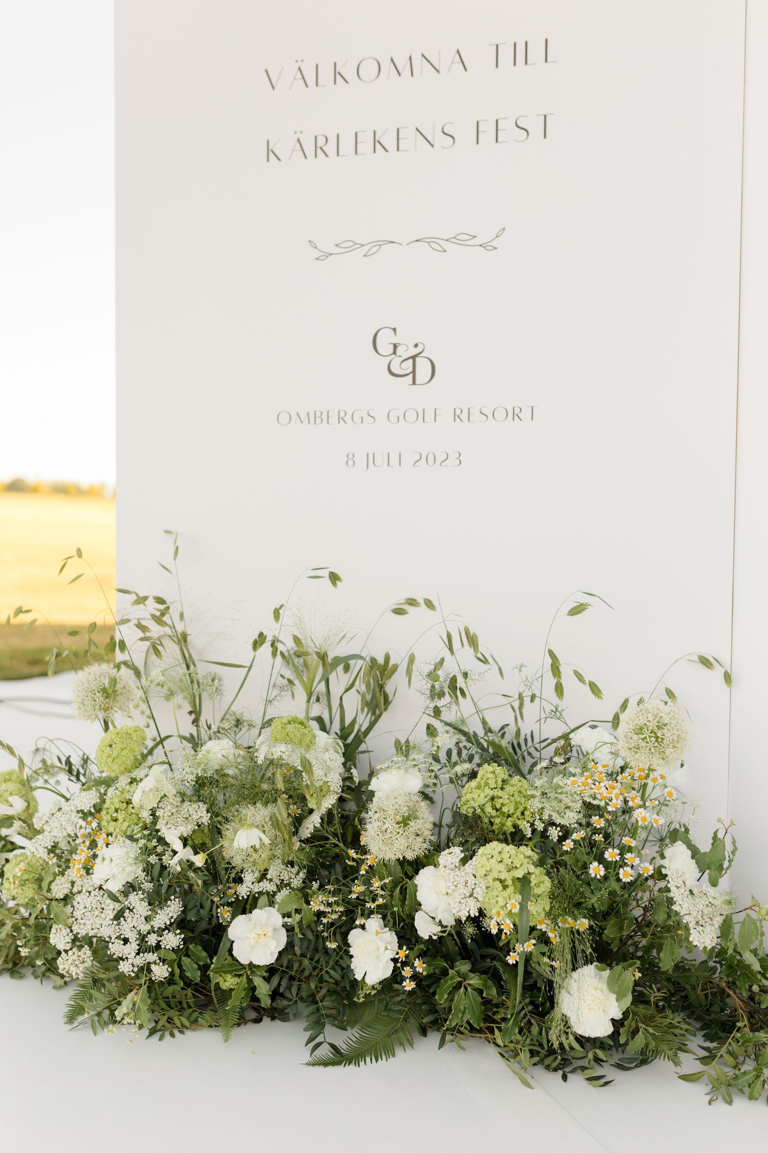 Elegant wedding welcome sign with white floral arrangement featuring hydrangeas and greenery at base, displayed at Oakbrook resort.