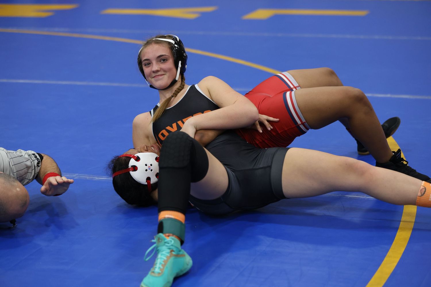 Wrestling match on blue mat with athletes engaged in ground combat.  Oviedo, Florida