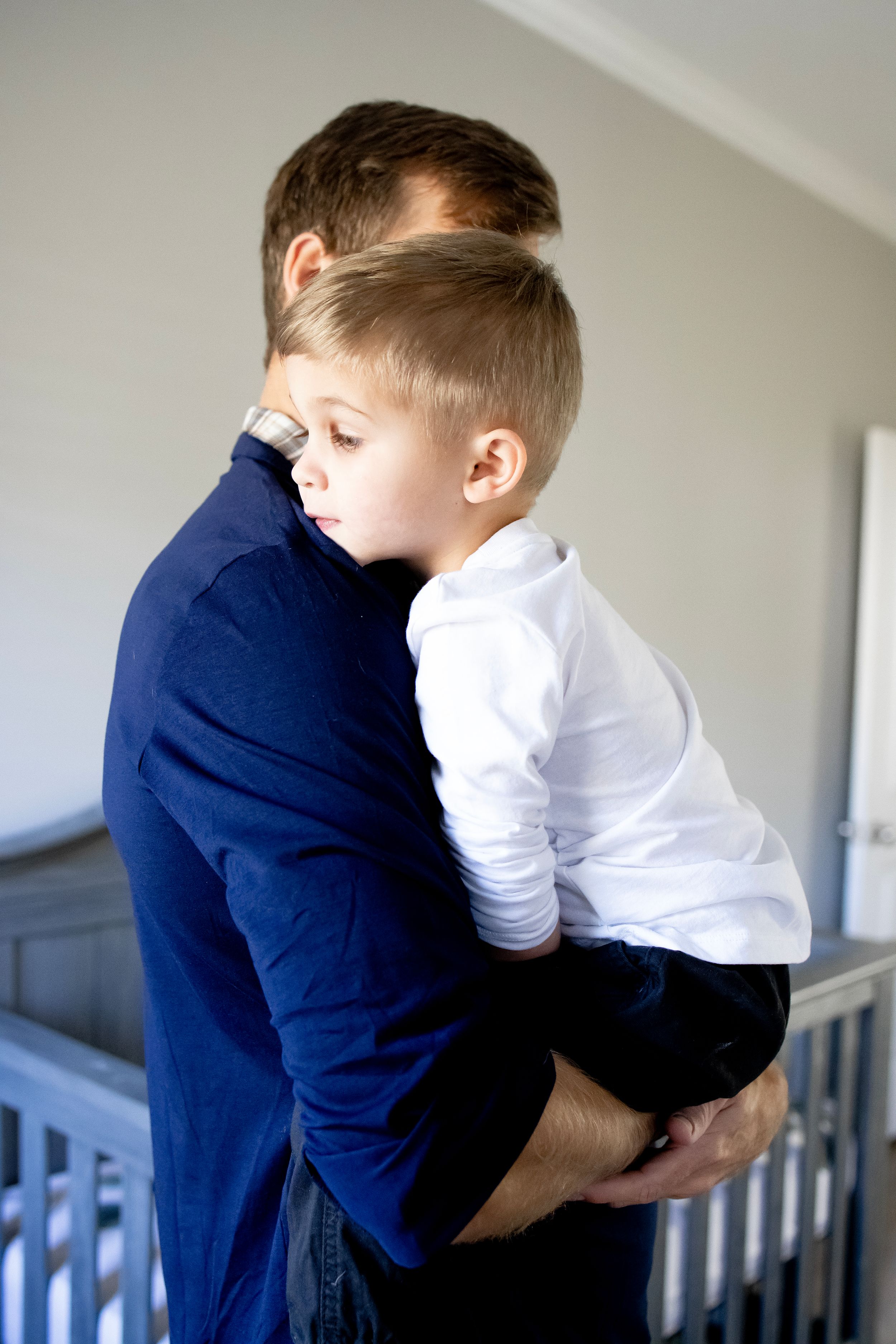 A touching moment between parent and child in casual attire standing by a crib.