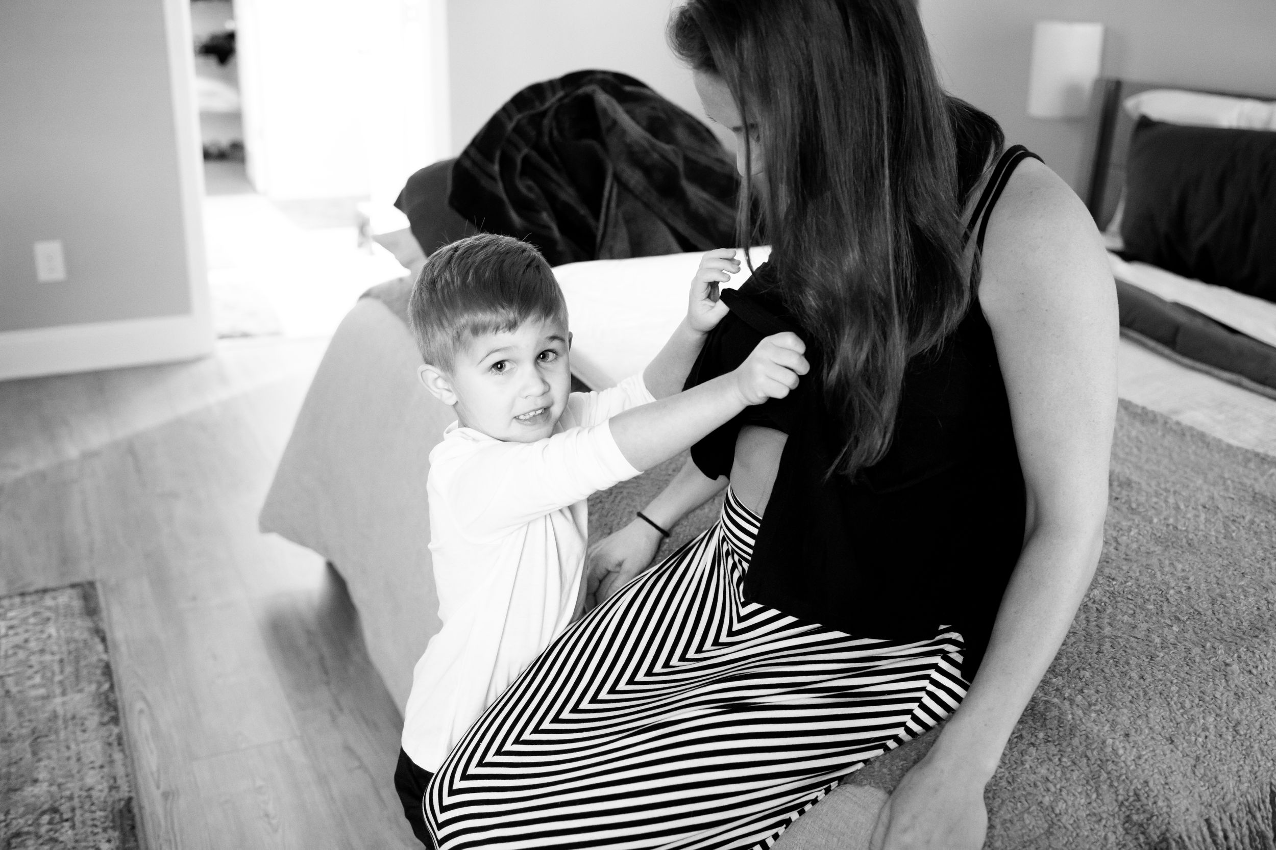 A black and white candid moment between parent and child sitting on carpet.
