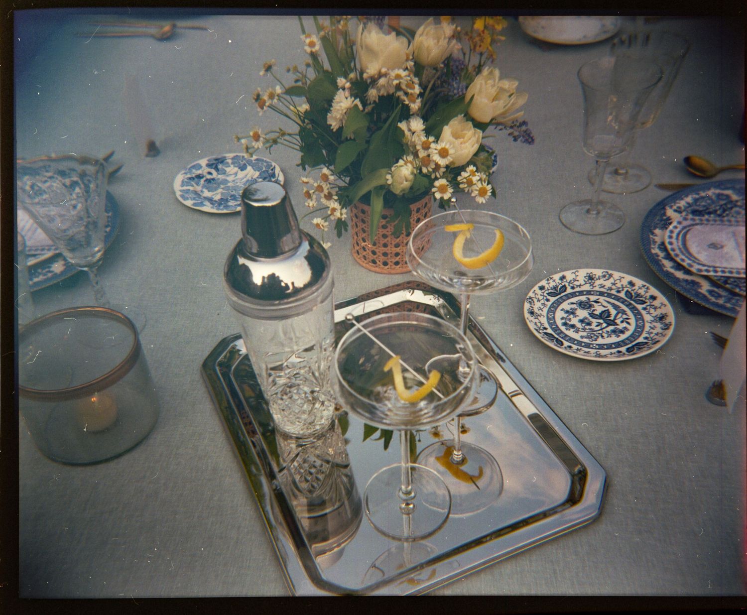 Vintage table setting with blue and white china, silver tray, and yellow floral centerpiece.