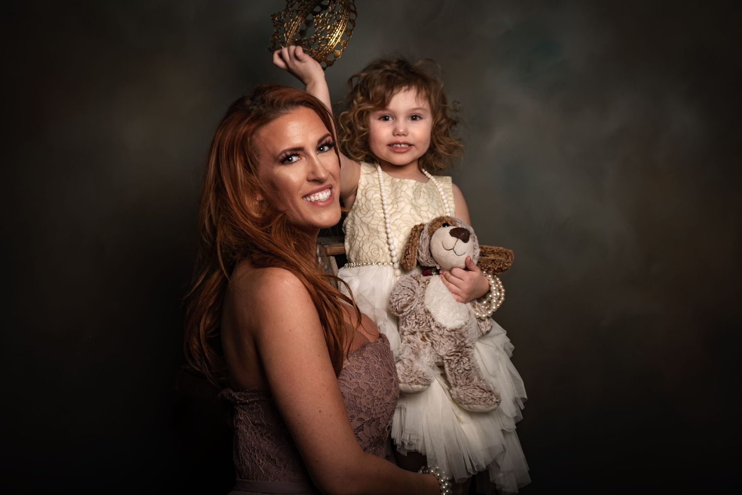 A heartwarming studio portrait with a child holding a stuffed animal in formal attire.