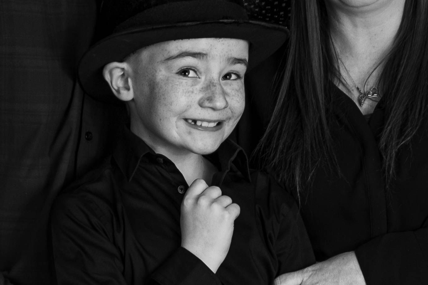 A black and white portrait of a child wearing a cap with a joyful expression.