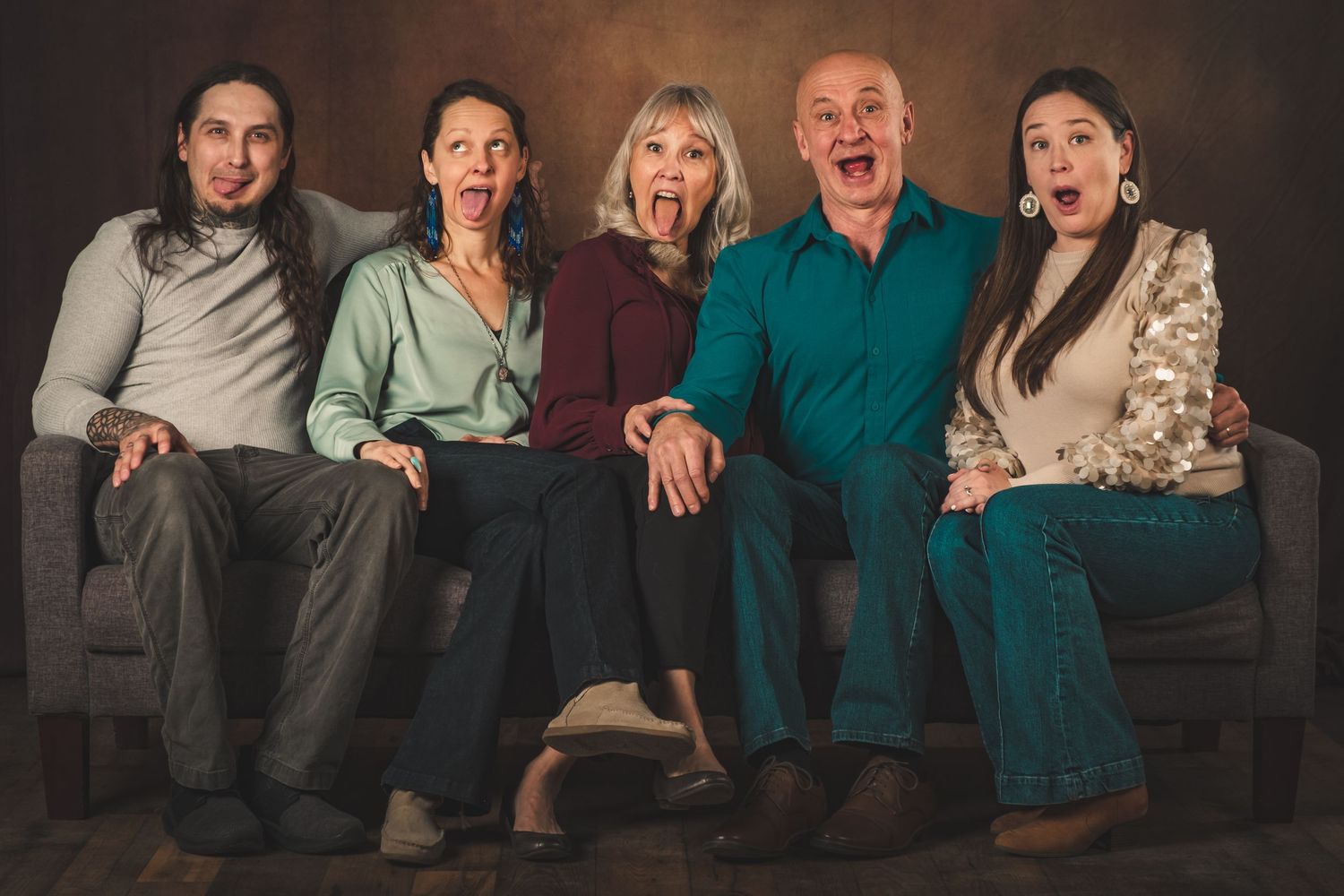 Five people sitting on a couch together showing different expressions and emotions. Family Photography