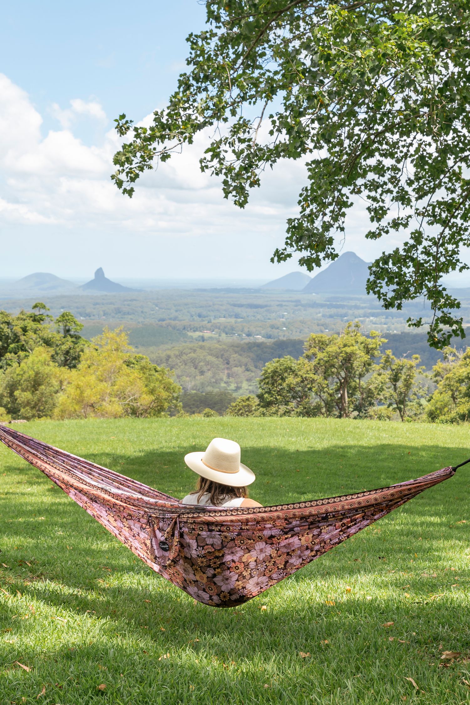 A colorful hammock stretched between trees with mountain views in the background.