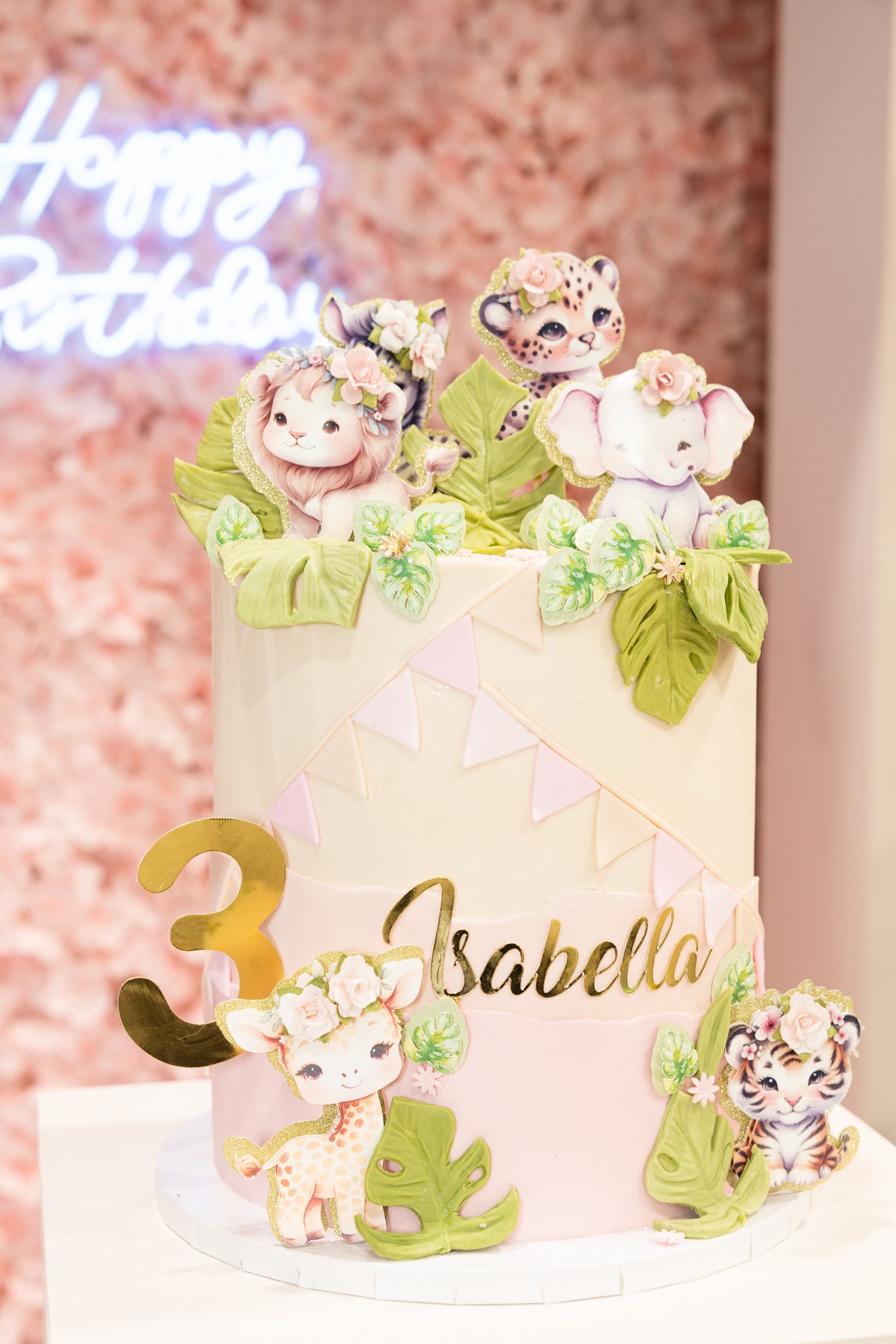 Whimsical safari-themed birthday cake with cute animal decorations and gold lettering.