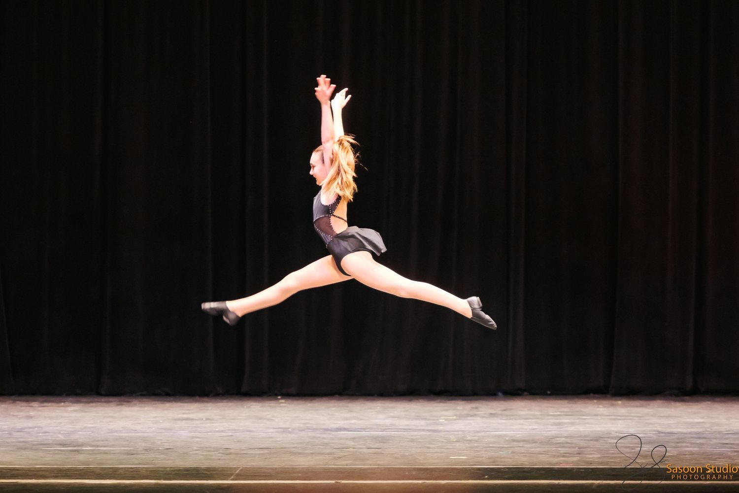 A dancer leaps gracefully through the air during a stage performance.