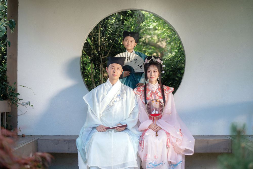 Candid natural light Hanfu family portrait of parents playing happily with kids at Botanic Garden Auckland, by Imagine Image Studio.