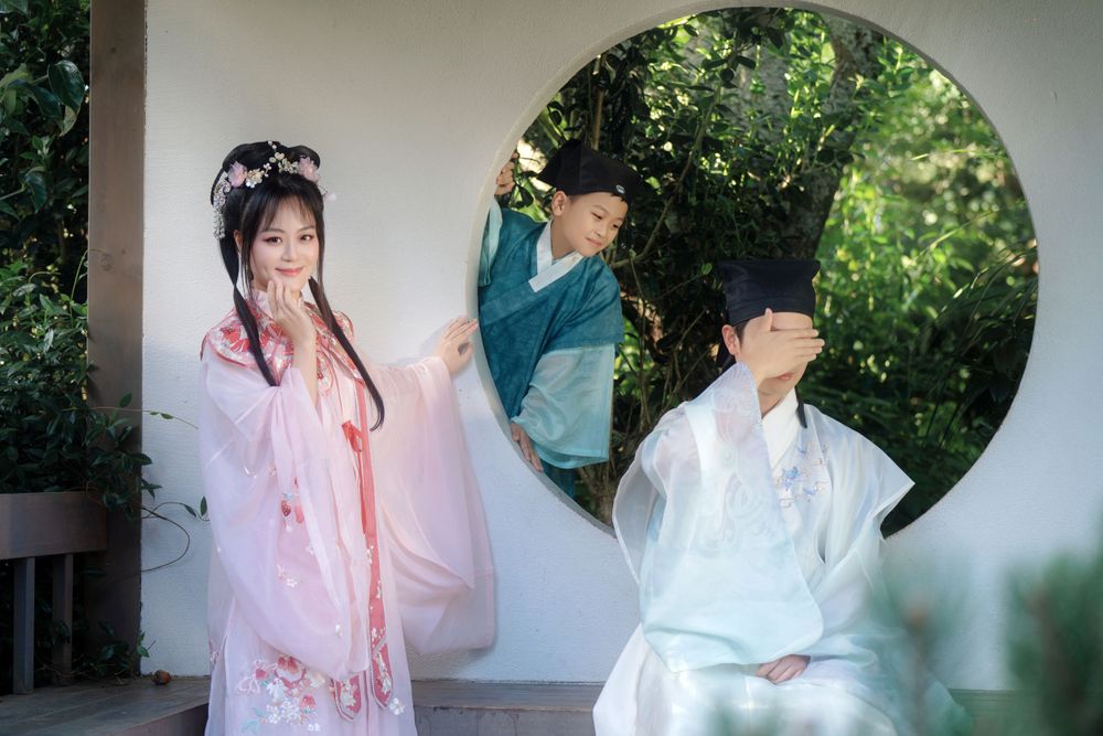 Candid natural light Hanfu family portrait of parents playing happily with kids at Botanic Garden Auckland, by Imagine Image Studio.