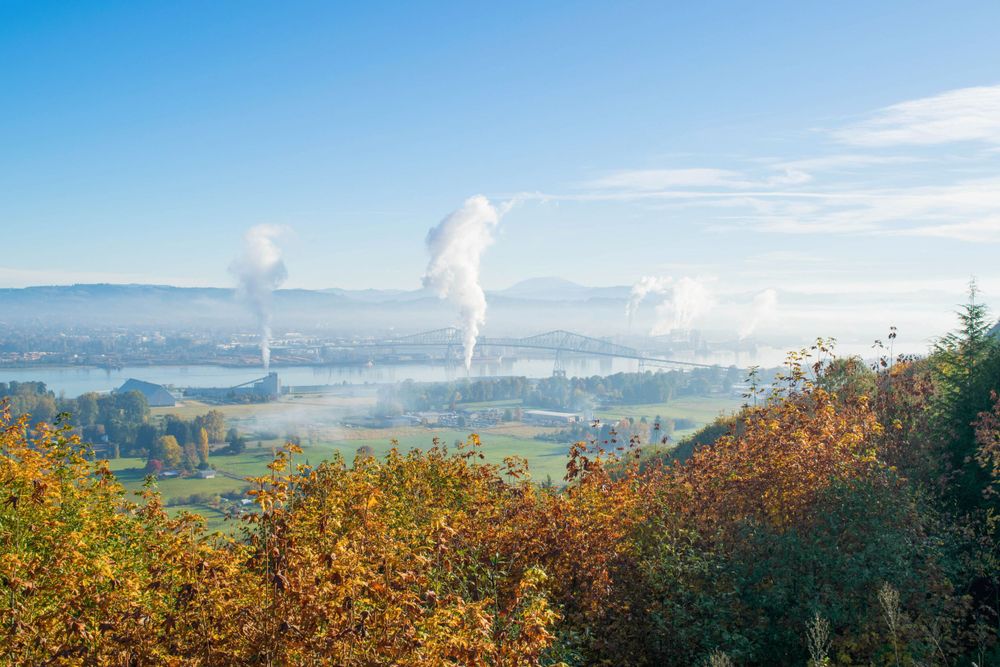 Fall landscape with steam rising from industrial plants in a misty valley.