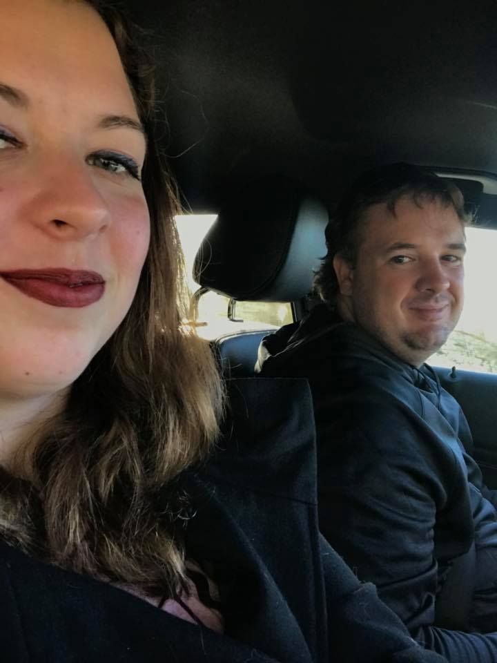 Two people taking a selfie while sitting in a car.