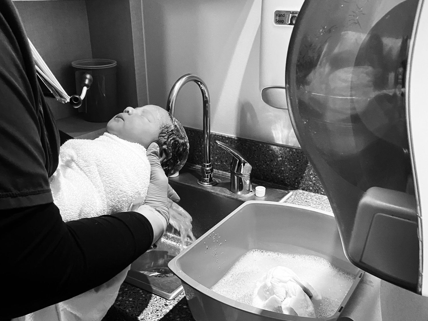 Hospital staff bathing a newborn infant in a medical sink.