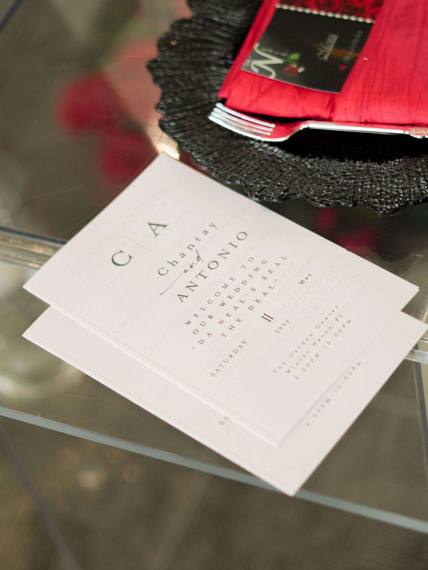 Wedding invitation and menu cards displayed on a reflective glass surface.